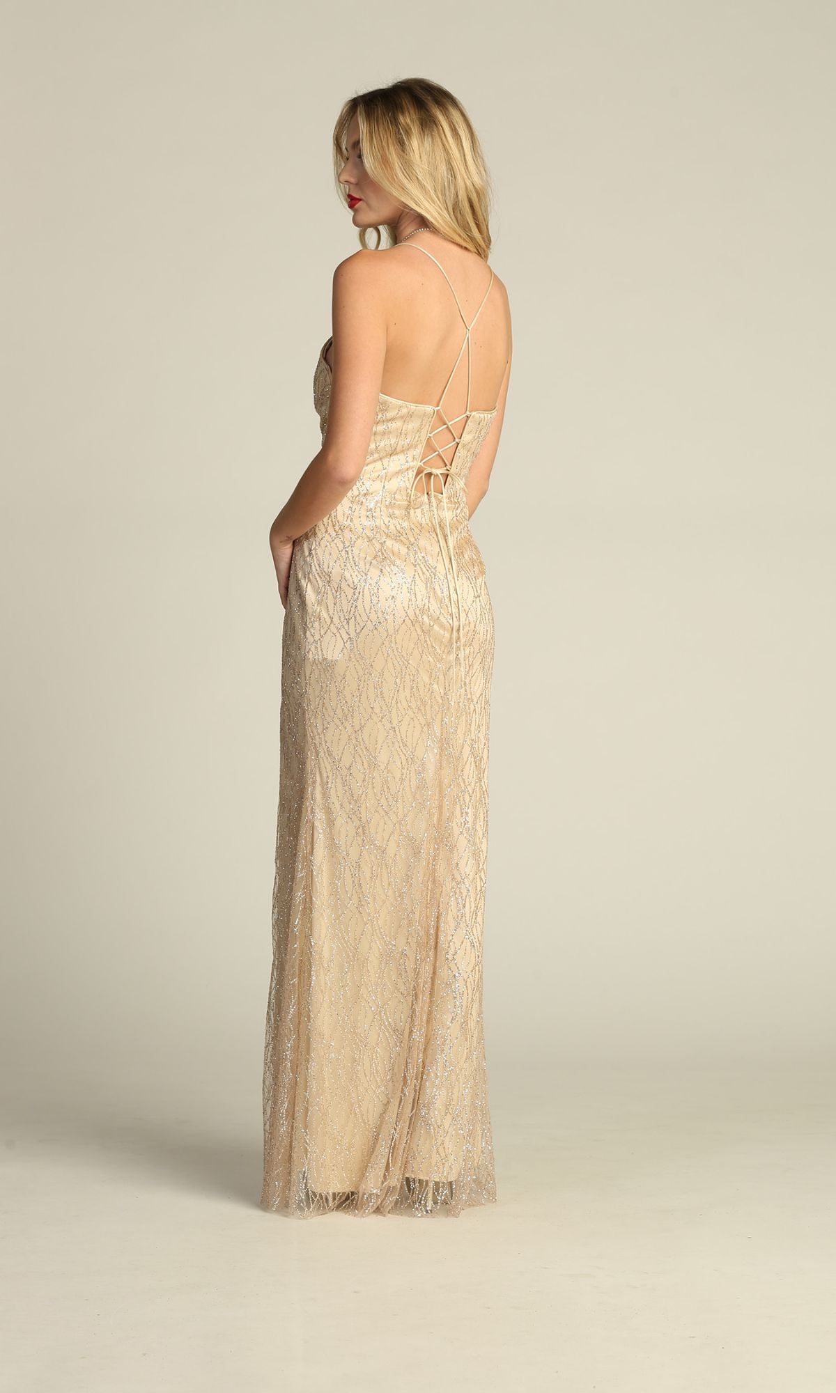 A woman stands at an angle against a plain background, showcasing the Corset-Back Glitter-Print Long Prom Dress 4023 with its floor-length silhouette and crisscross strappy back.